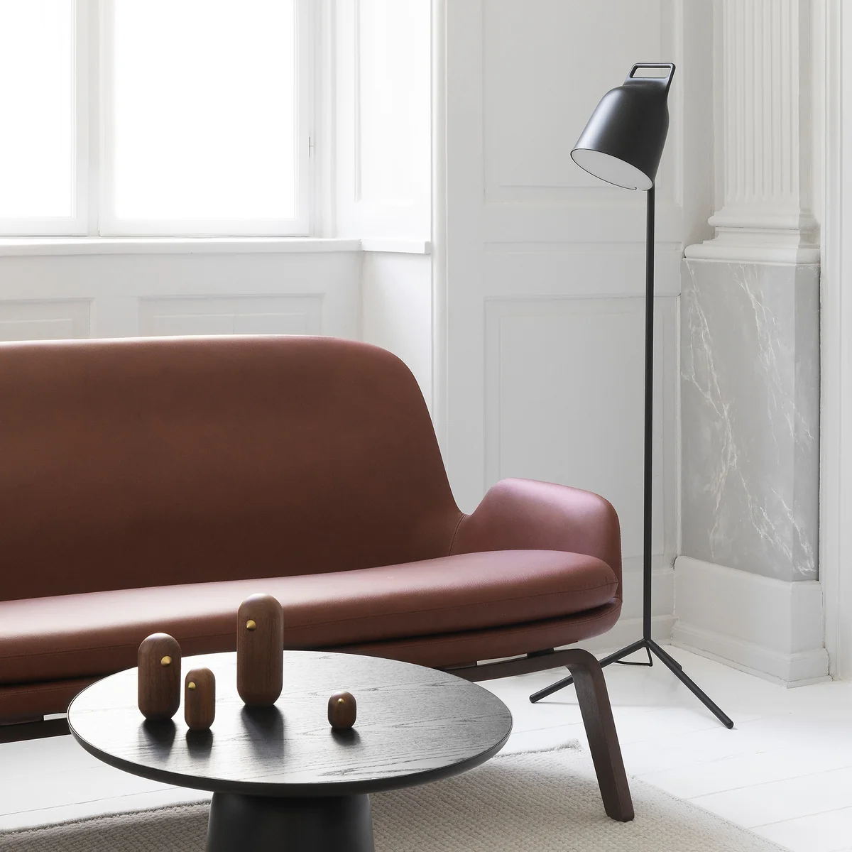 Le Stage Lampadaire LED de Normann Copenhagen à côté d'un canapé en cuir brun
