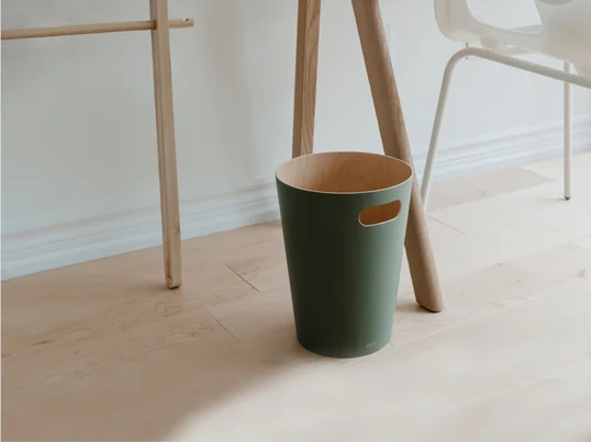 La corbeille à papier Woodrow d'Umbra dans la vue d'ambiance : La corbeille à papier minimaliste devient un accessoire spécial sous le bureau grâce à la couche de couleur extérieure.