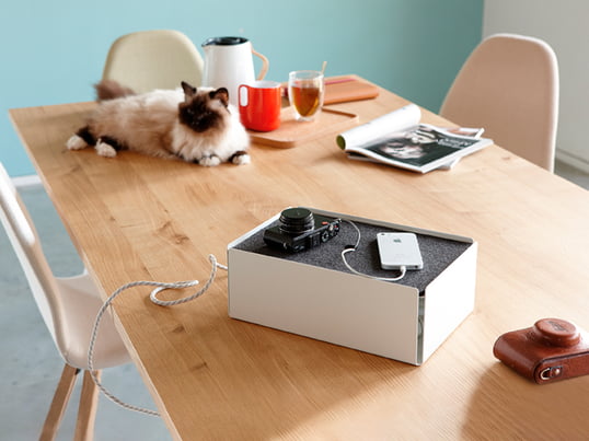 La boîte de chargement de Konstantin Slawinski dans la vue d'ambiance : La boîte cache les câbles de chargement des iPhones, des appareils photo et d'autres dispositifs avec style sur la table de cuisine.