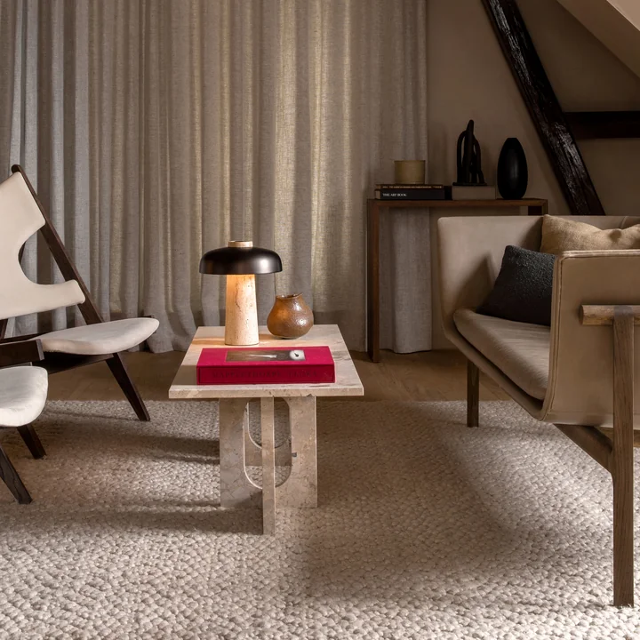 La table de salon Androgyne de Audo en tant que table basse entre le canapé et les chaises de salon dans des couleurs naturelles.