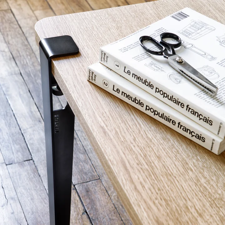 Le pied de table et de bureau, noir graphite de TipToe sur une table de travail avec des livres et des ciseaux