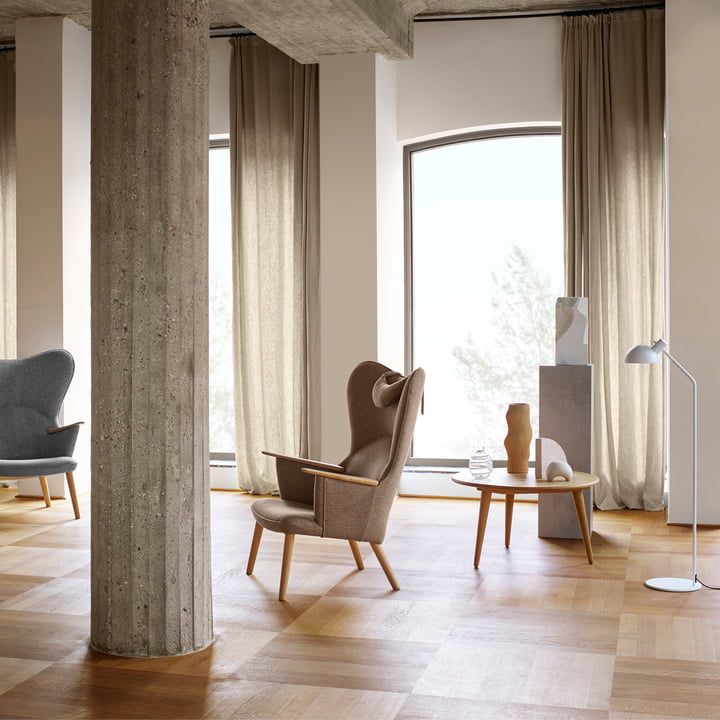 Le CH78 Mama Bear Lounge Chair de Carl Hansen dans une pièce lumineuse avec des colonnes en pierre et un sol en bois