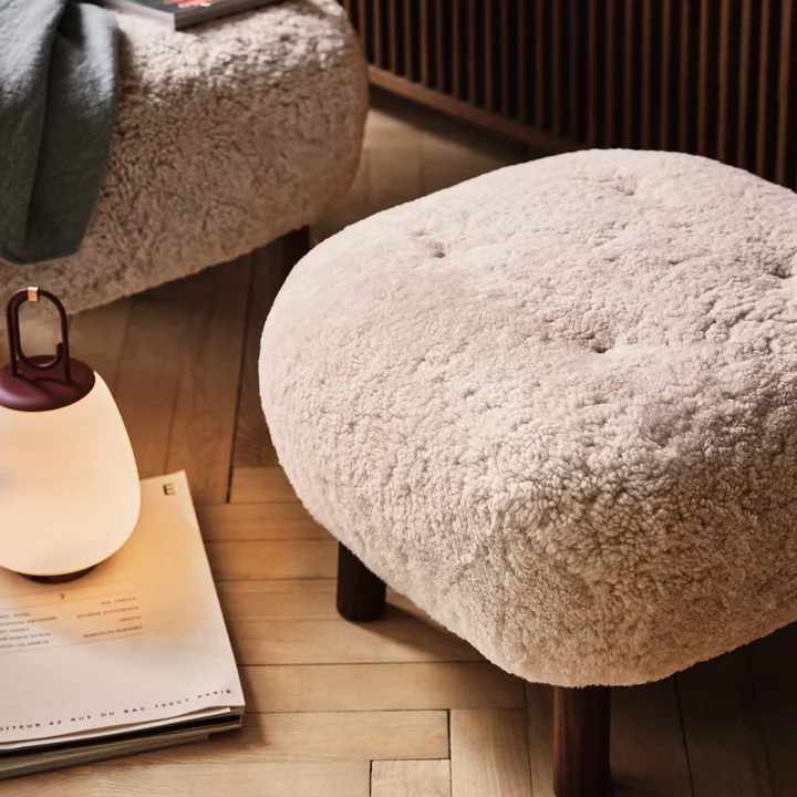 Le Pouf ATD1 de & tradition sur un plancher de bois clair à côté d'un autre pouf