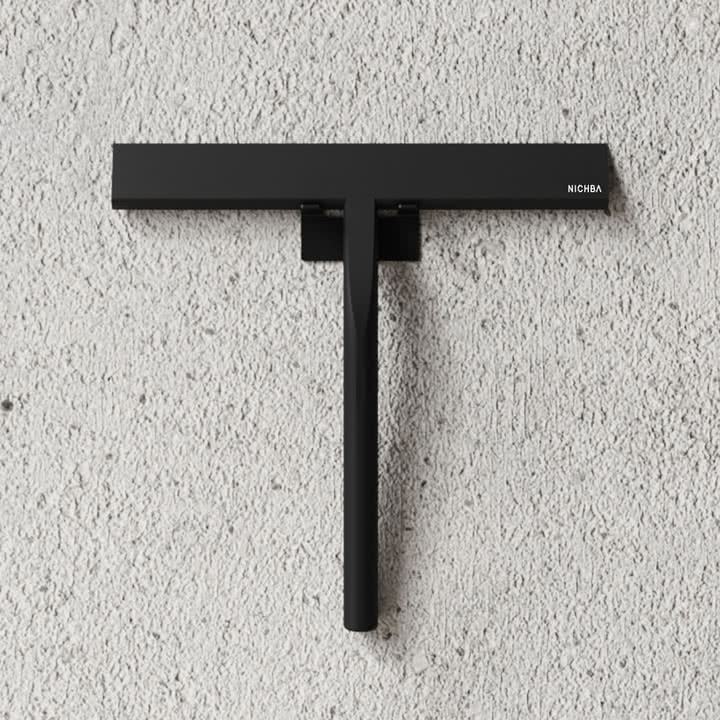 La raclette de douche de Nichba Design sur un mur de pierre