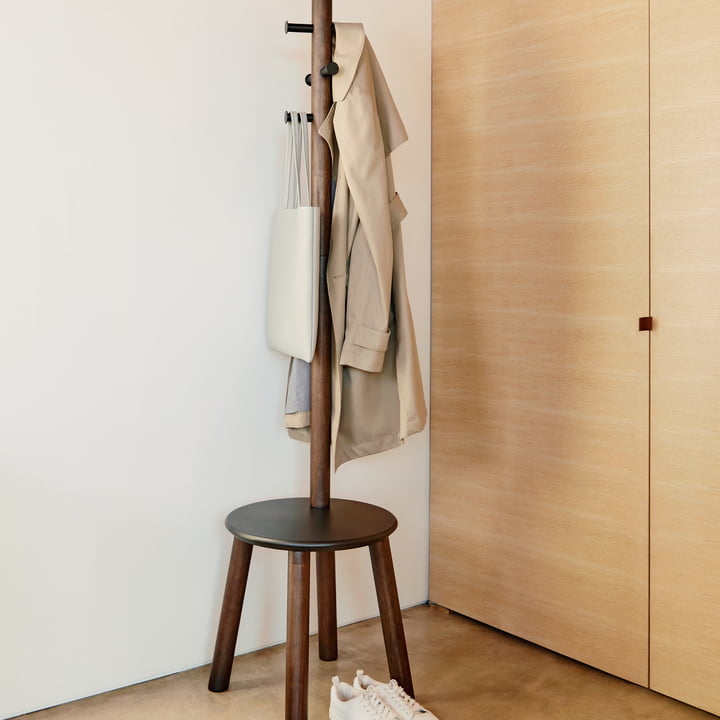 Le tabouret / portemanteau Pillar de Umbra comme lieu de stockage pour les vestes et les sacs à côté d'une armoire murale lumineuse