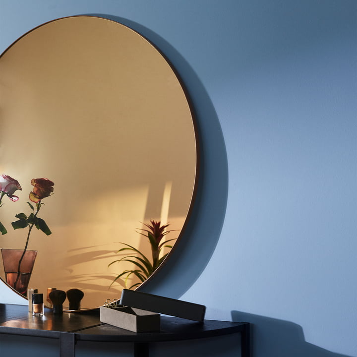 Le miroir mural Circum de AYTM avec verre coloré dans la couleur ambre sur un sideboard noir