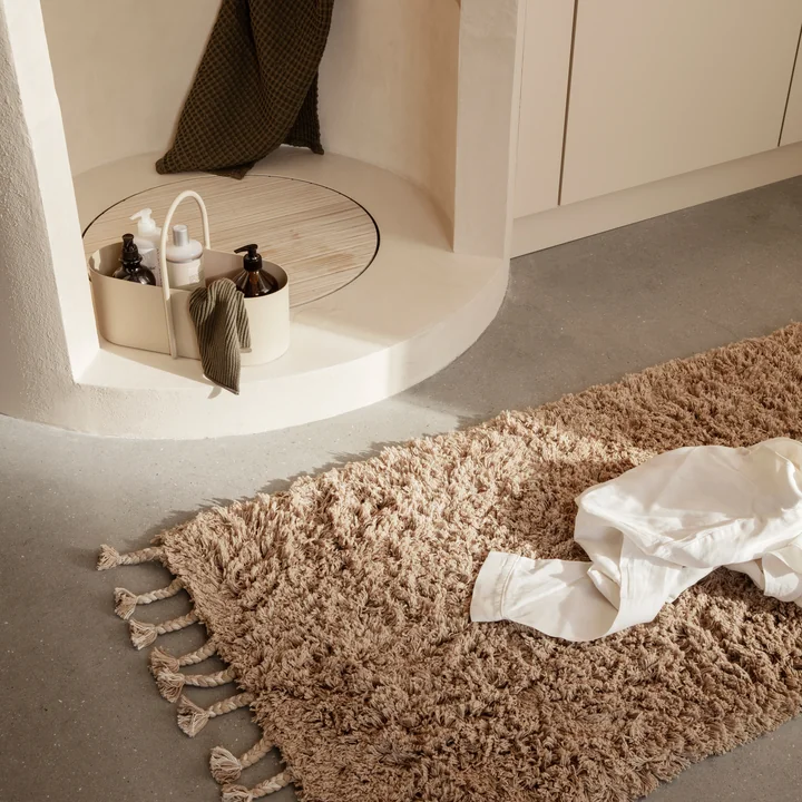 Le tapis à poils longs Amass de Ferm Living à côté de la douche en pierre dans la salle de bain