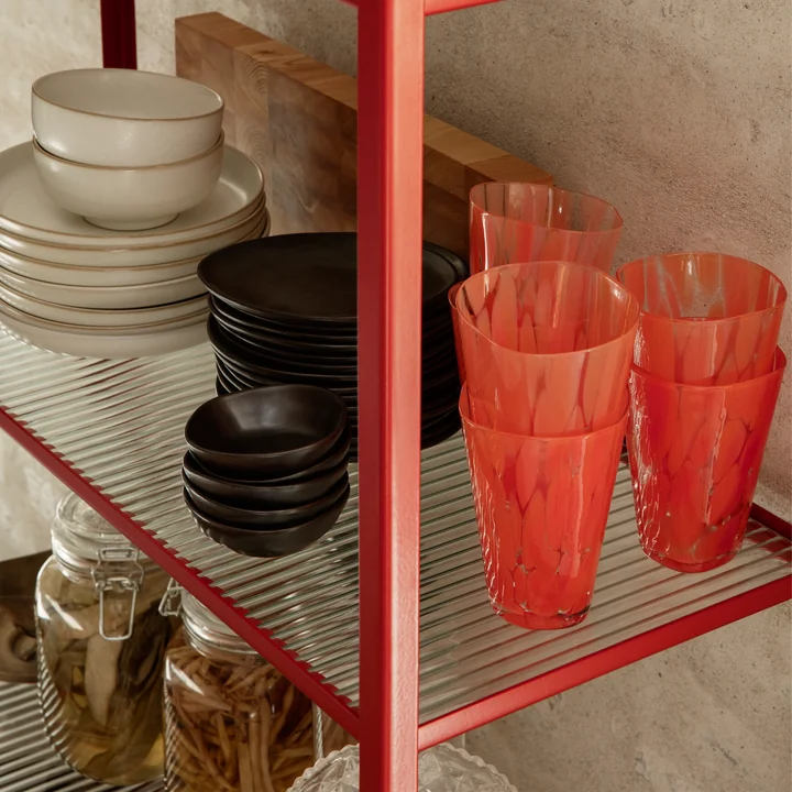 Le verre à boire Casca de Ferm Living in poppy red sur une étagère murale à côté d'autres articles de table