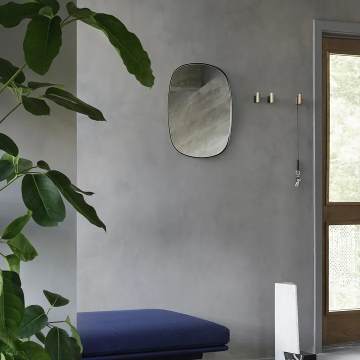 Le Framed Mirror Klein de Muuto dans le couloir au-dessus d'un banc bleu et à côté de crochets muraux nobles