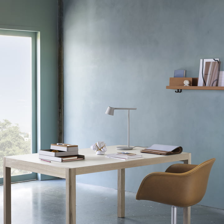 Le site Tip lampe de table de Muuto sur un bureau clair avec une chaise de bureau en cuir