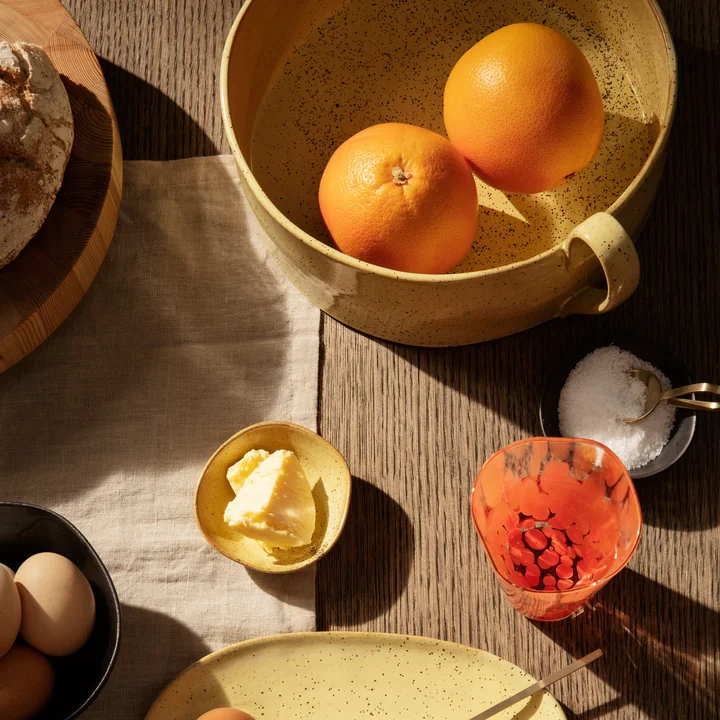 La coupe à fruits Flow de Ferm Living sur la table du petit-déjeuner avec des oranges, du pain et du beurre.