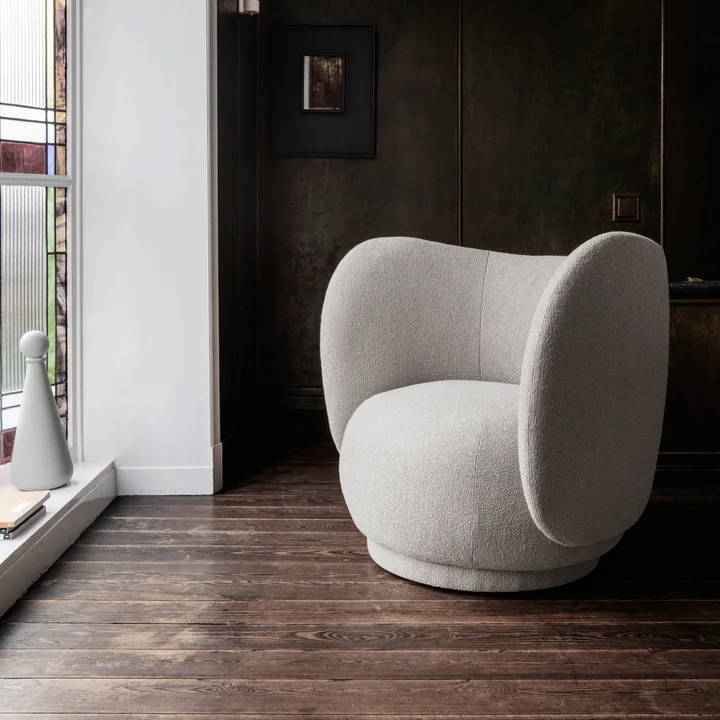 Le Rico Lounge Chair de Ferm Living sur un parquet foncé devant une baie vitrée