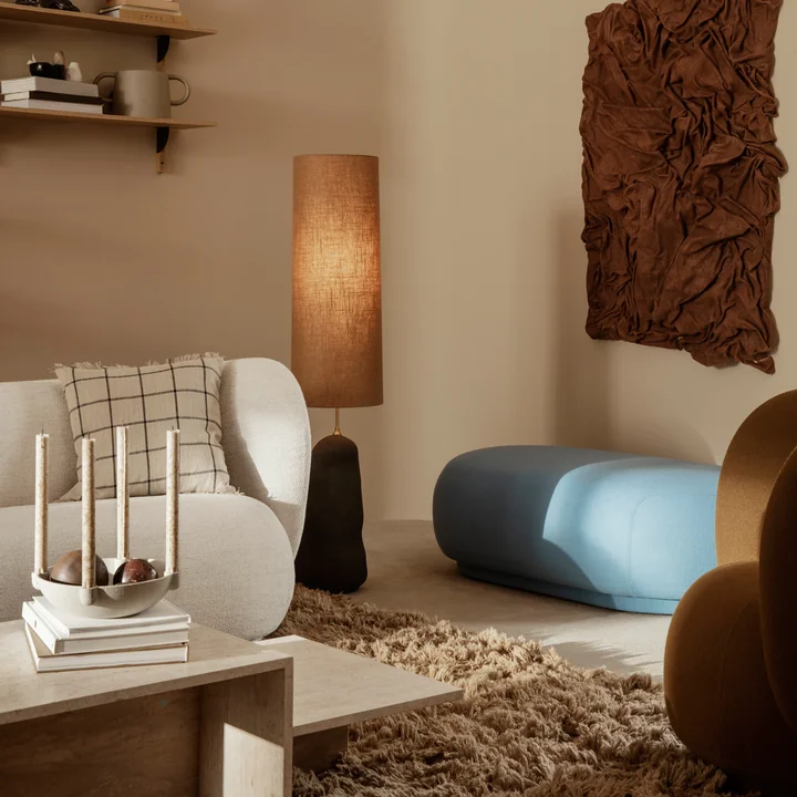 Le canapé Rico de Ferm Living sur un tapis marron derrière une table basse en travertin