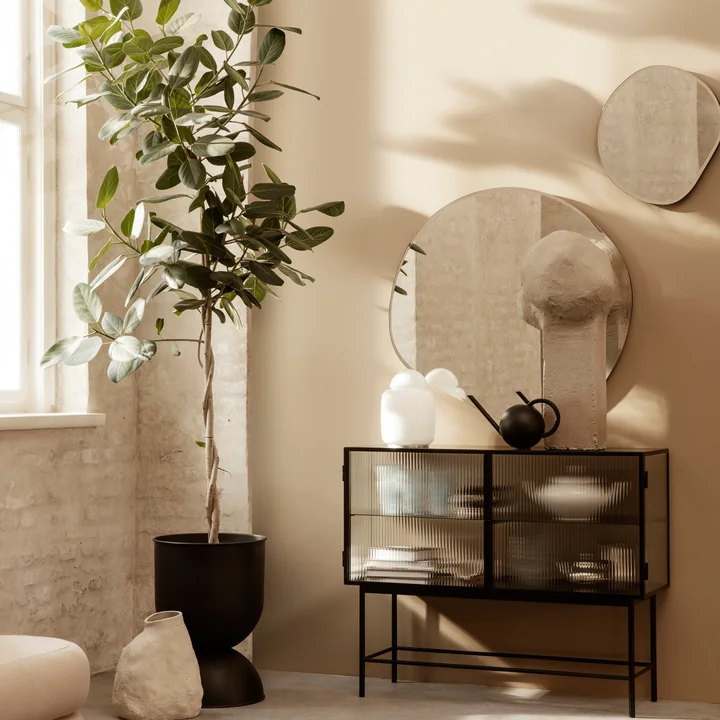 Le miroir Pond de Ferm Living au-dessus d'un sideboard artistiquement décoré
