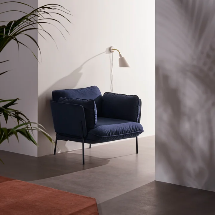 L'applique Bellevue AJ9 de & tradition en blanc à côté d'un noble fauteuil bleu dans le hall