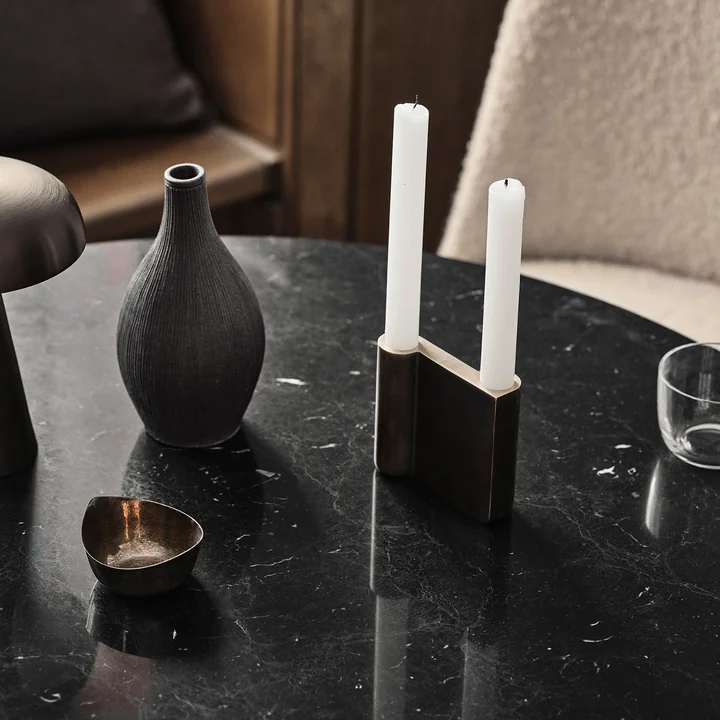 Le bougeoir Collect de & Tradition avec des bougies blanches sur une table en marbre noir