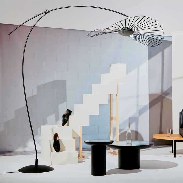 Le lampadaire Vertigo Nova de Petite Friture en noir dans un salon lumineux avec un escalier blanc et une table d'appoint noire