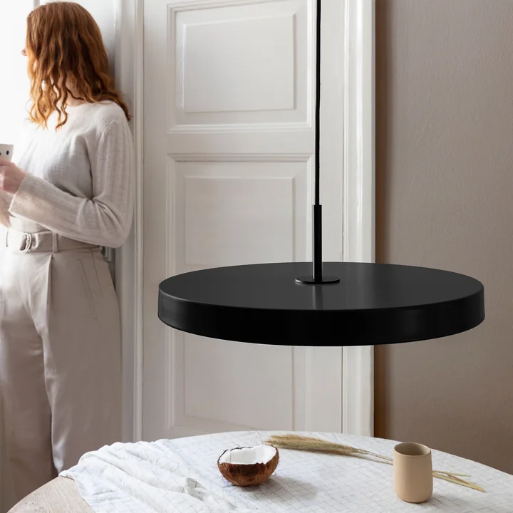 La suspension LED Asteria de Umage en noir / noir au-dessus d'une table à manger ronde blanche