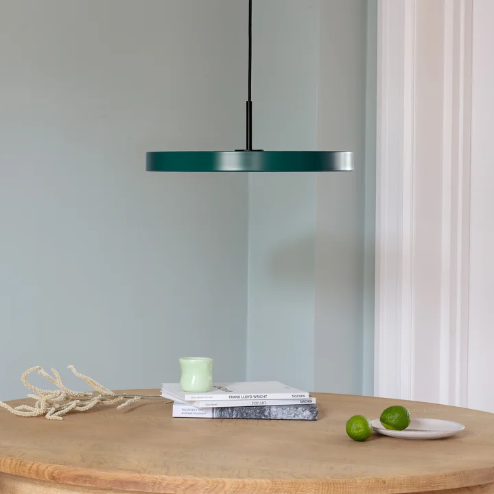 La suspension LED Asteria de Umage en noir / forest green au-dessus d'une table à manger ronde en bois clair