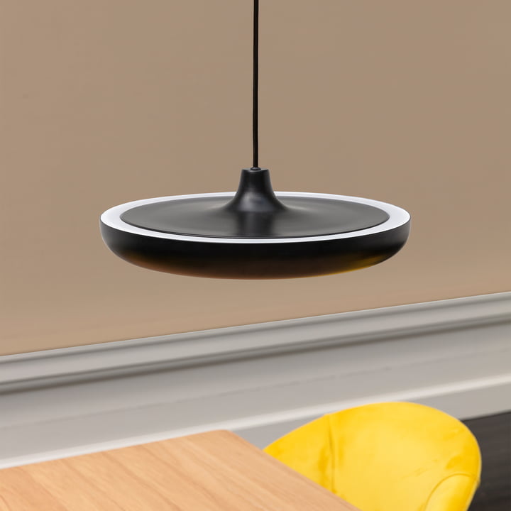 La suspension LED Cassini Medium de Umage en noir au-dessus d'une table en bois avec une chaise jaune