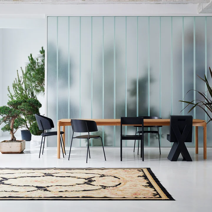 Le Wagner Dining Chair de OUT Objekte unserer Tage en anthracite à une grande table de salle à manger en bois à côté d'autres chaises sombres