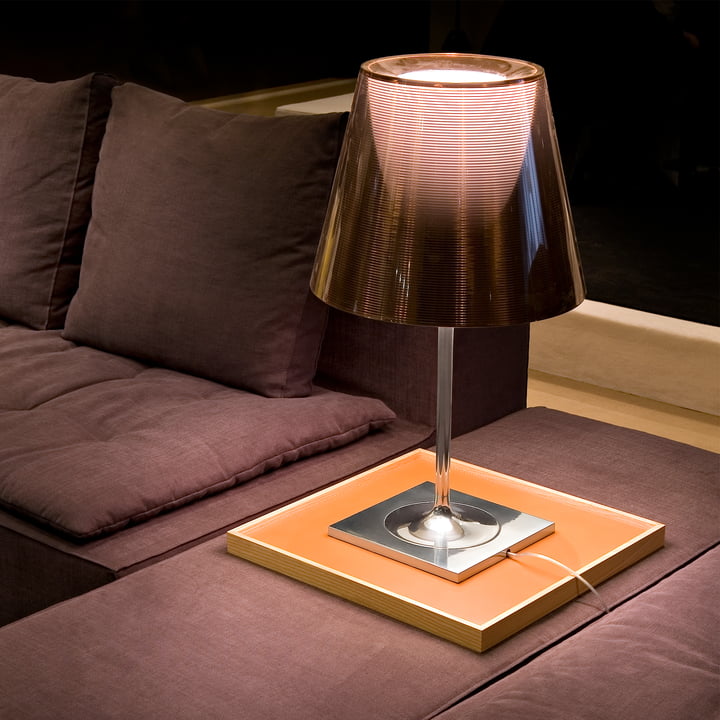 Le K Tribe Lampe de table T2 de Flos avec abat-jour transparent dans un coin sombre du canapé