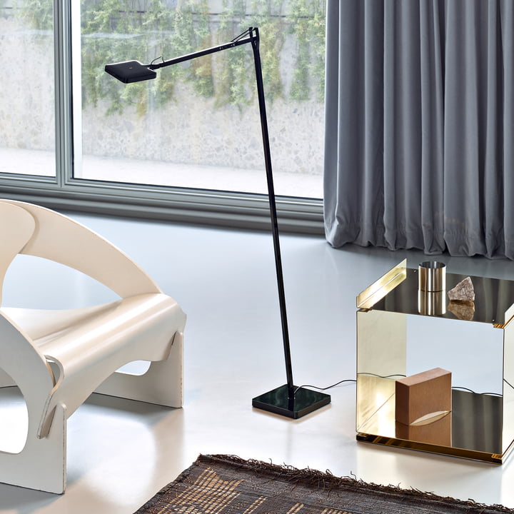 Le lampadaire Kelvin LED F de Flos en noir à côté d'une chaise longue blanche et d'une table d'appoint dorée