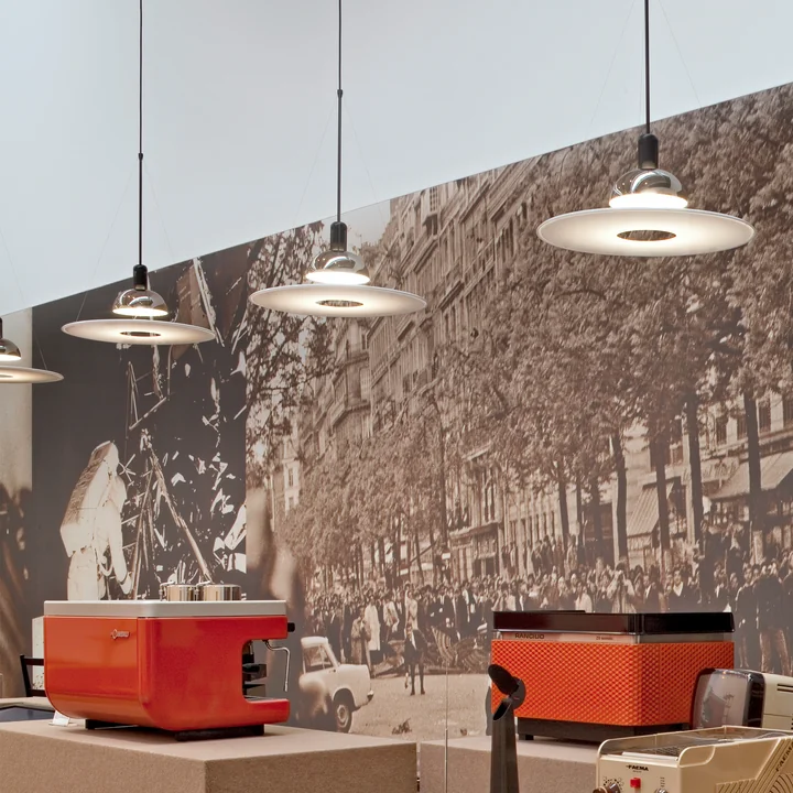 Les lumières du pendentif Frisbi de Flos dans un restaurant devant une grande photo