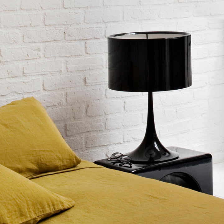 Le Spun Light T2 de Flos en noir sur une table d'appoint noire à côté d'un canapé jaune