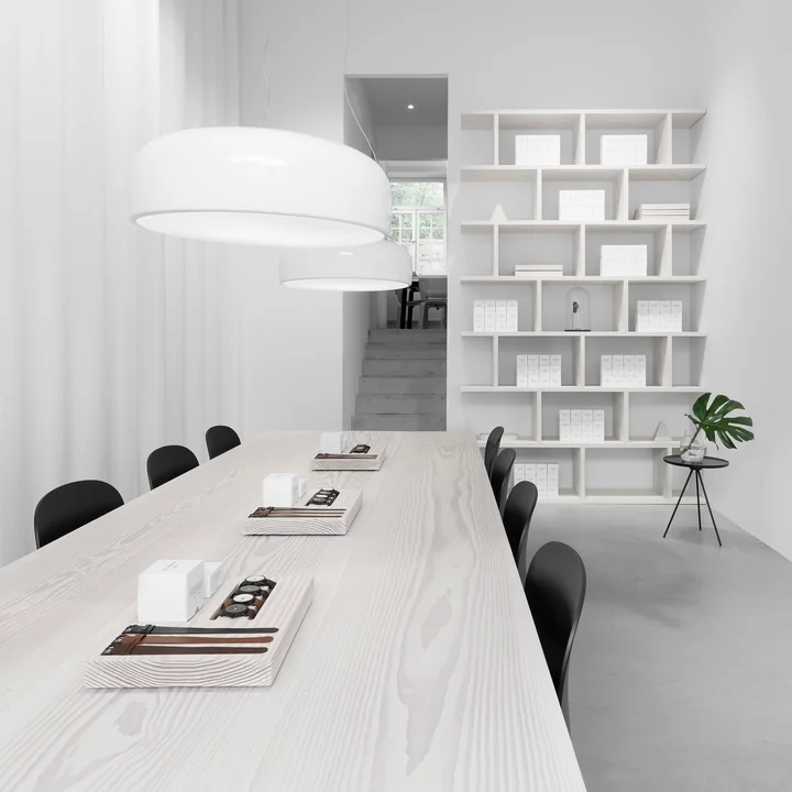 La lampe à suspension Smithfield Pro de Flos en blanc au-dessus d'une longue table dans une pièce blanche