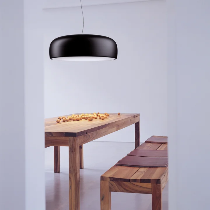 Le luminaire suspendu Smithfield Pro de Flos en noir mat au-dessus d'une table à manger en bois naturel