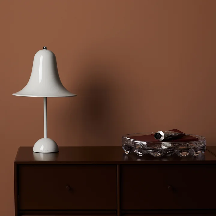 La lampe de table gris menthe Pantop de Verpan sur une commode en bois foncé