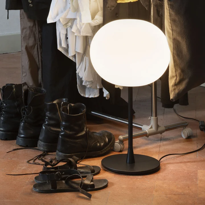 La lampe de table Glo-Ball de Flos en noir à côté d'une armoire sur le sol