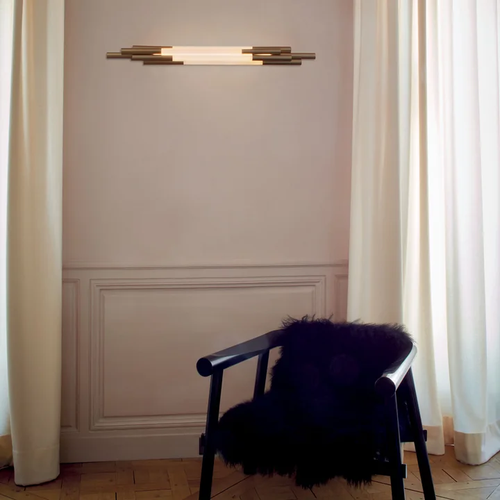 La lampe murale Org LED de DCW sur le mur du salon au-dessus d'un fauteuil