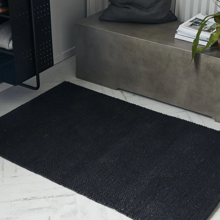 Le tapis noir Hempi de House Doctor devant un banc en béton
