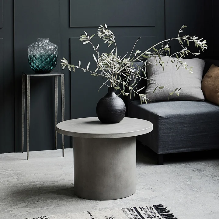 Stone La table d'appoint en béton de House Doctor devant un canapé gris dans le salon