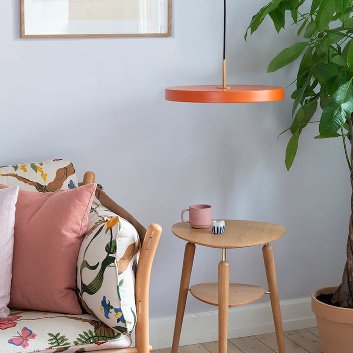 La lampe orange Asteria Suspension de Umage au-dessus de la table d'appoint