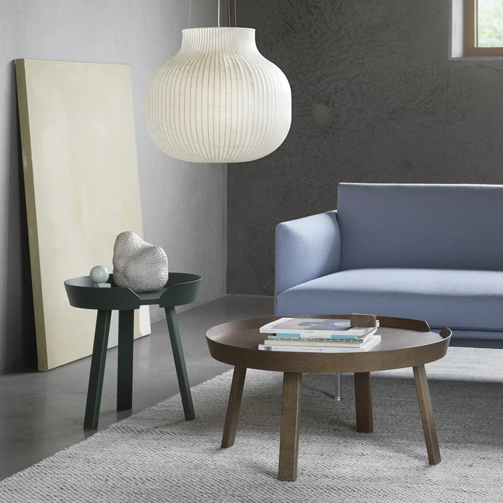 Le Around des tables de Muuto à côté d'un canapé bleu clair dans le salon
