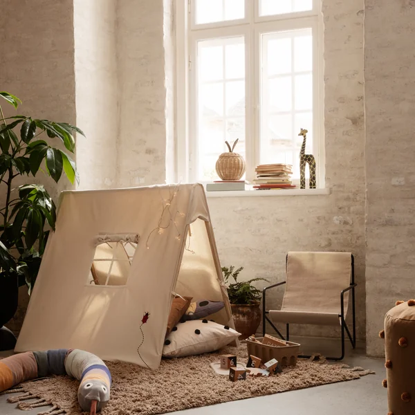 La Desert Chair Kids de Ferm Living dans une chambre d'enfant meublée de manière organique avec une tente de jeu et un tapis douillet.