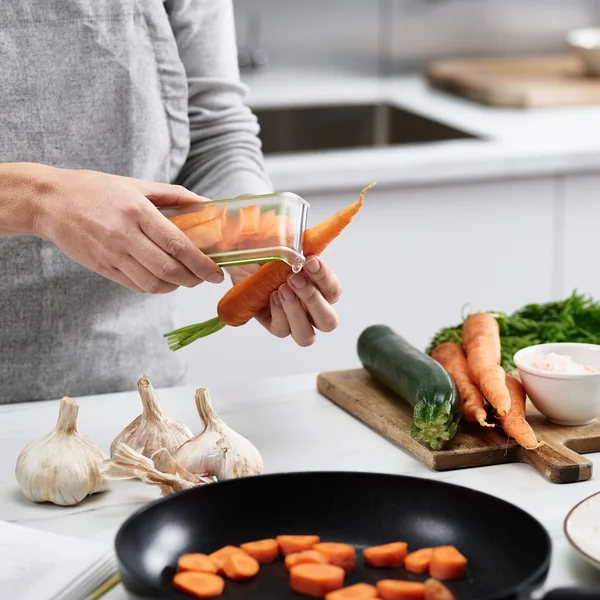 L'éplucheur PeelStore avec bac à déchets de Joseph Joseph assure la propreté lors de l'épluchage.